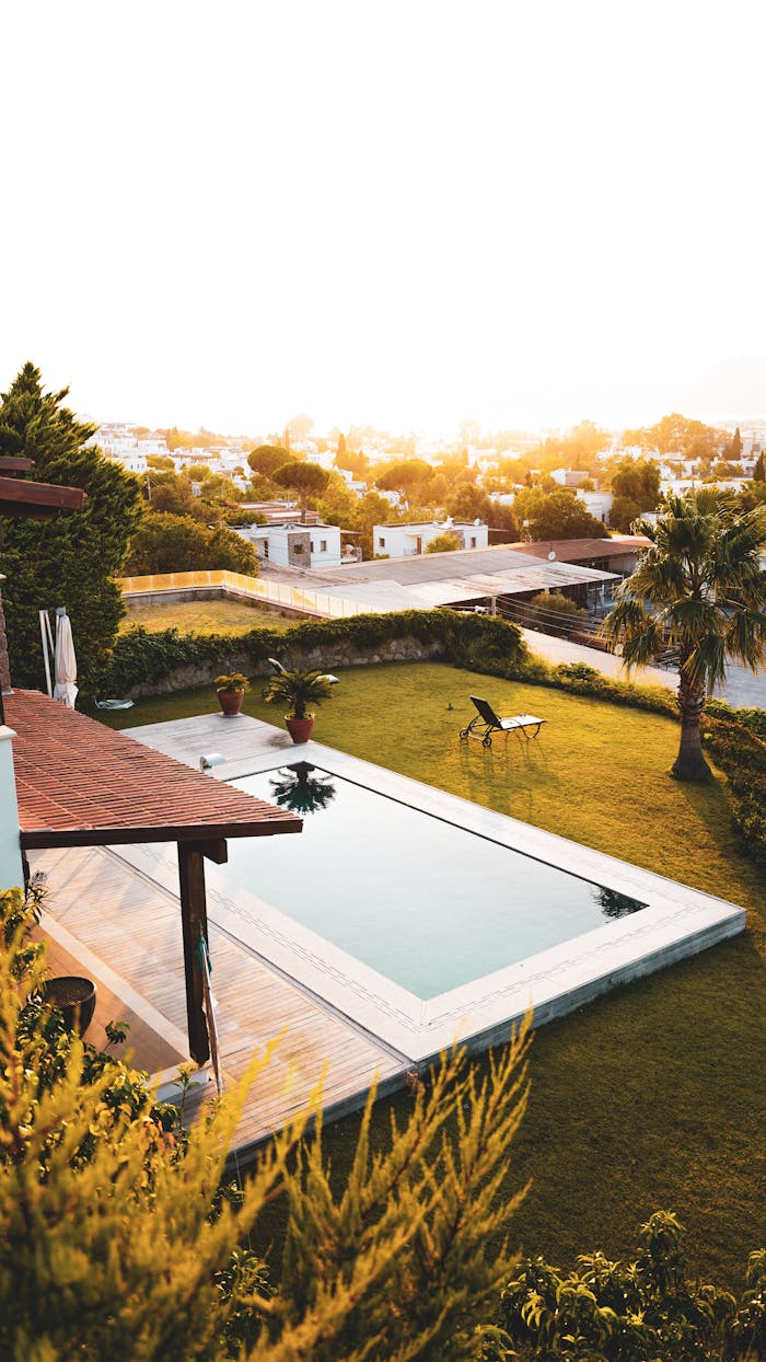 Stunning aerial image of a luxurious backyard with a swimming pool during a warm sunset.